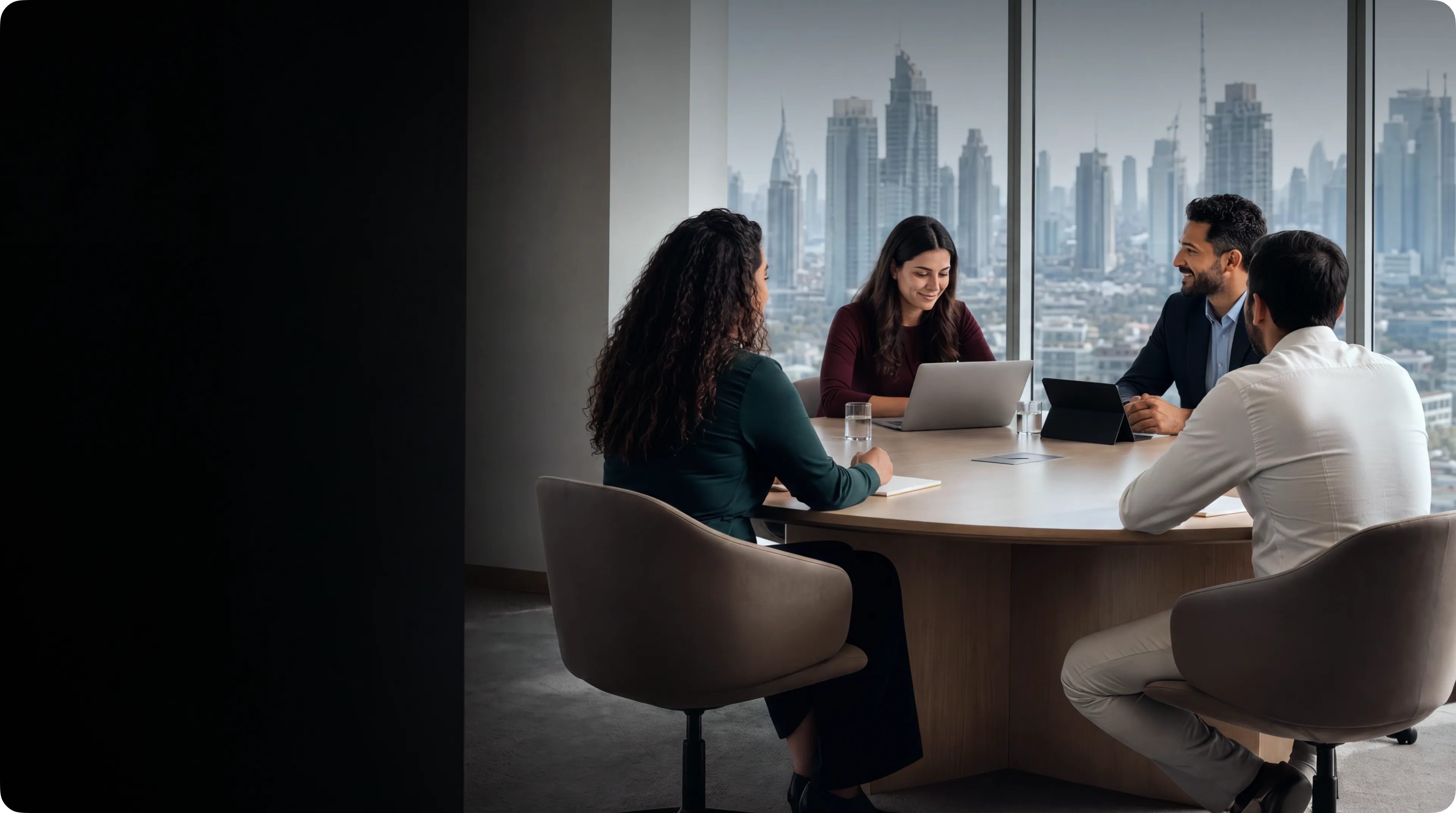 A team of four meeting around a table in an office overlooking a city skyline